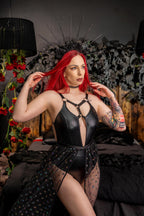 Woman with red hair wearing a black  bodysuit in a dark, decorative setting.