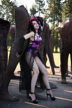 Person in a bodysuit with large wooden sculptures in an outdoor setting