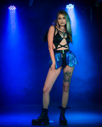 Person wearing a black bodysuit and blue skirt with blue lighting on a dark background