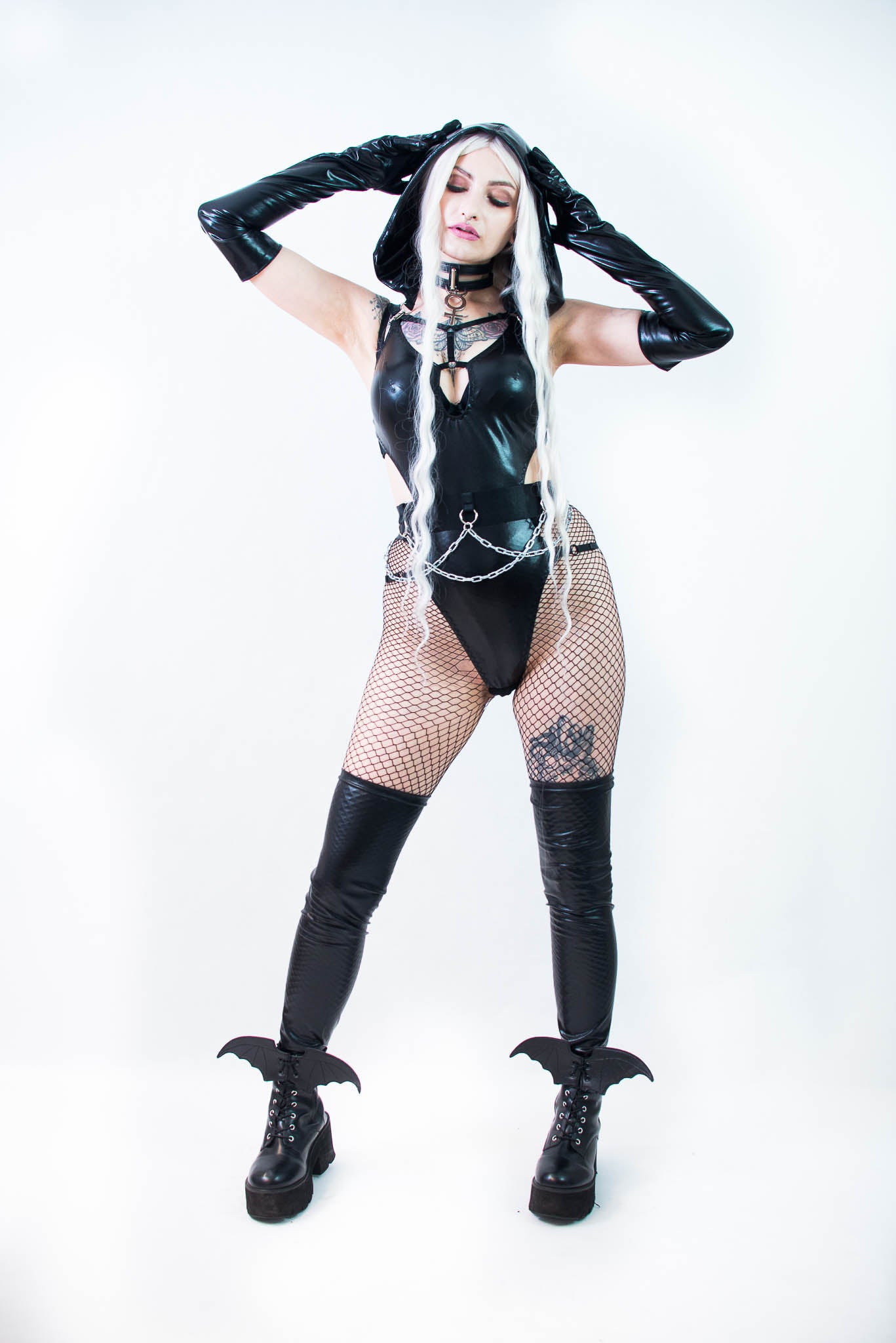 Person wearing a black bodysuit  with fishnet stockings on a white background