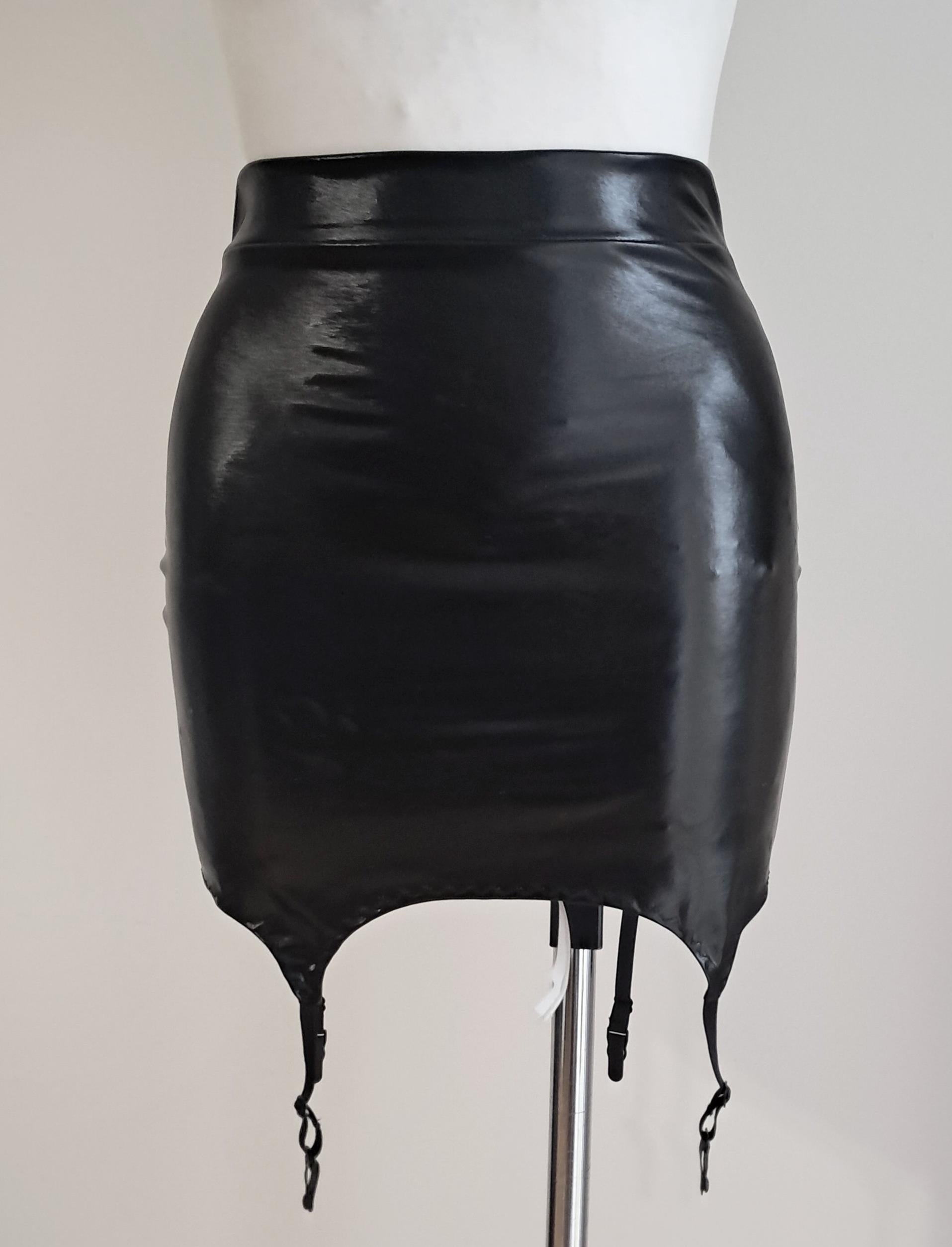 Black wet look mini skirt with suspenders on a mannequin against a plain background