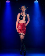 Person wearing a black top and red wet look mini skirt with suspenders with blue stage lights in the background