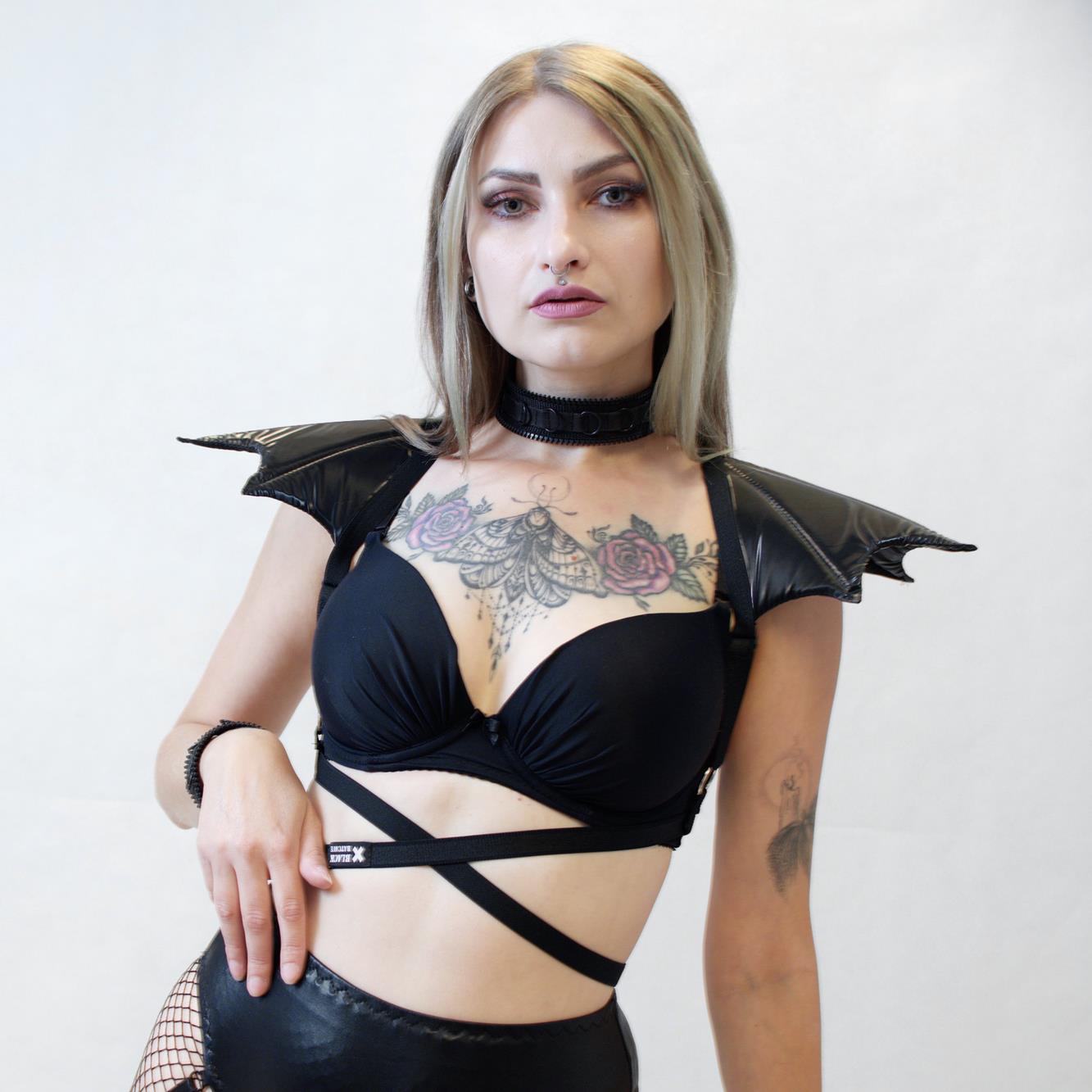 Woman wearing a harness with bat wings epaulets against a white background