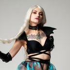 Woman in harness with bat wings epaulets with tattoos on a gray background