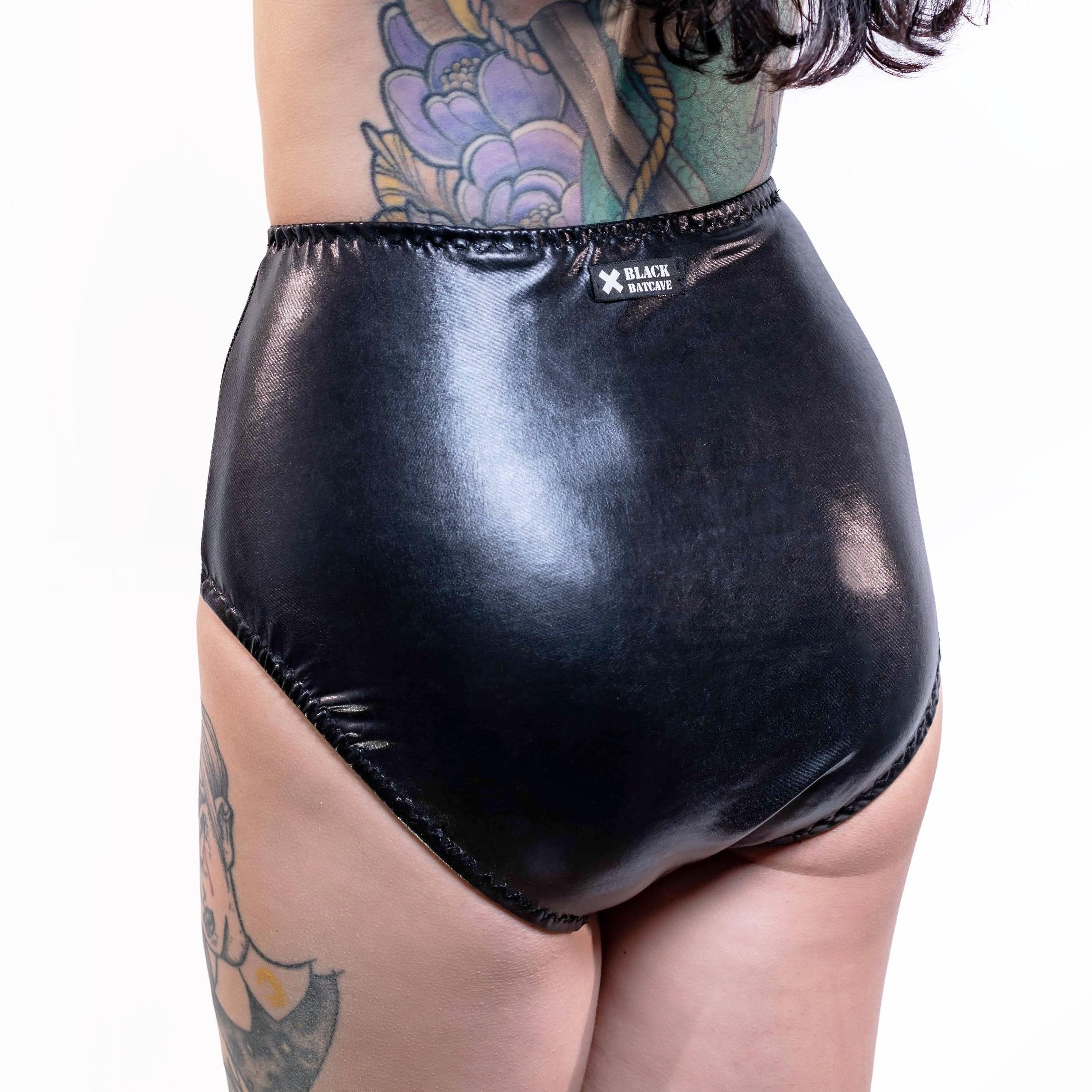 Blackwet-look high waist panties worn by a person with tattoos on a white background