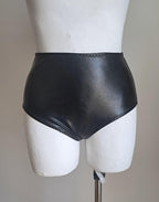 Black wet-look high waist panties on a mannequin against a plain background