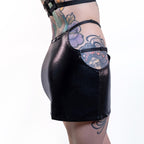 Black wet-look cut-out mini skirt worn by a person with tattoos on a white background