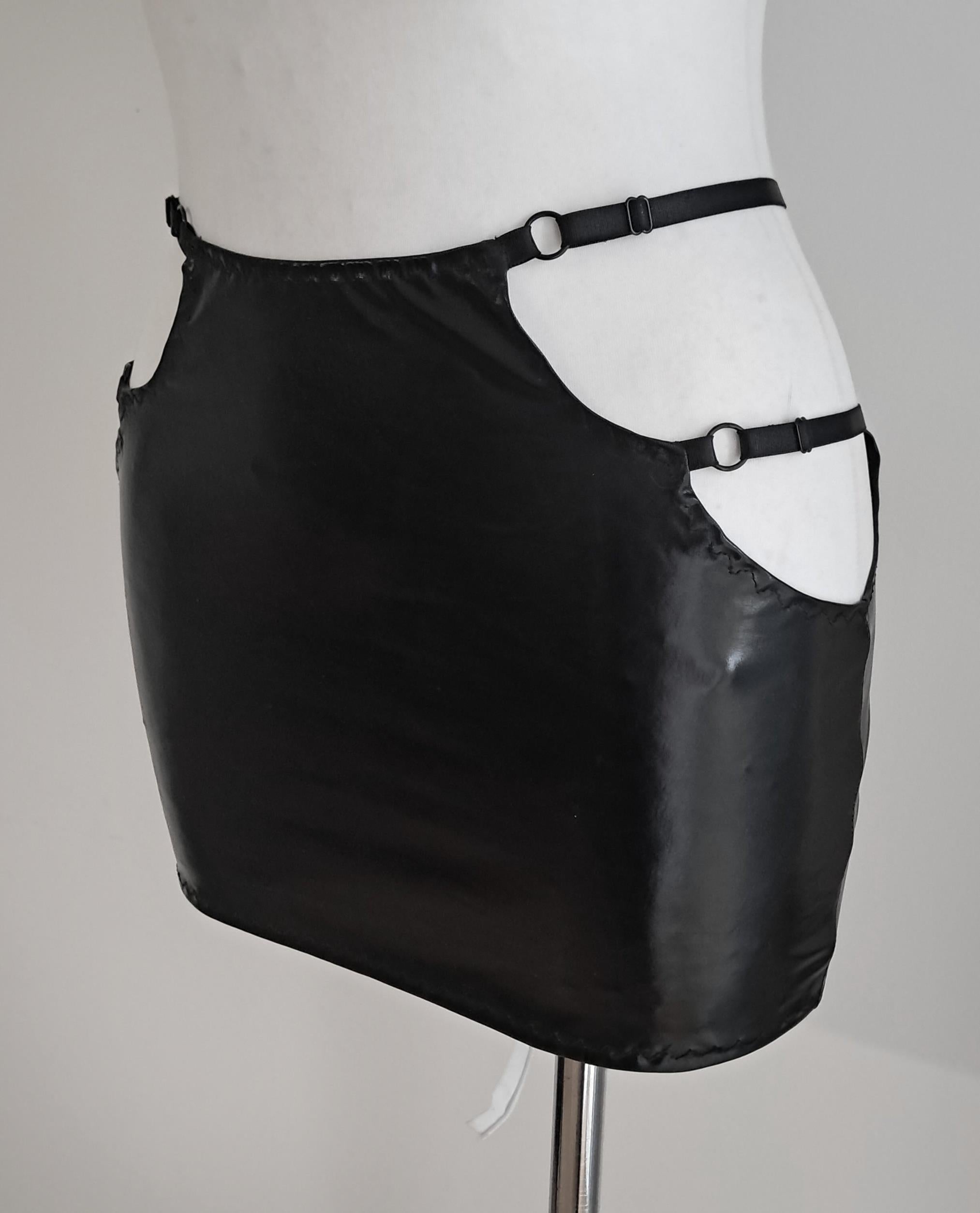 Black wet-look cut-out mini skirt on a mannequin against a gray background