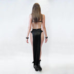 Woman wearing a black wet look cut-out dress with a high slit on a white background