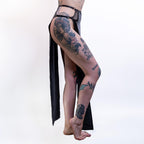 Person wearing black wet-look cut-out maxi skirt with tattoos on a white background