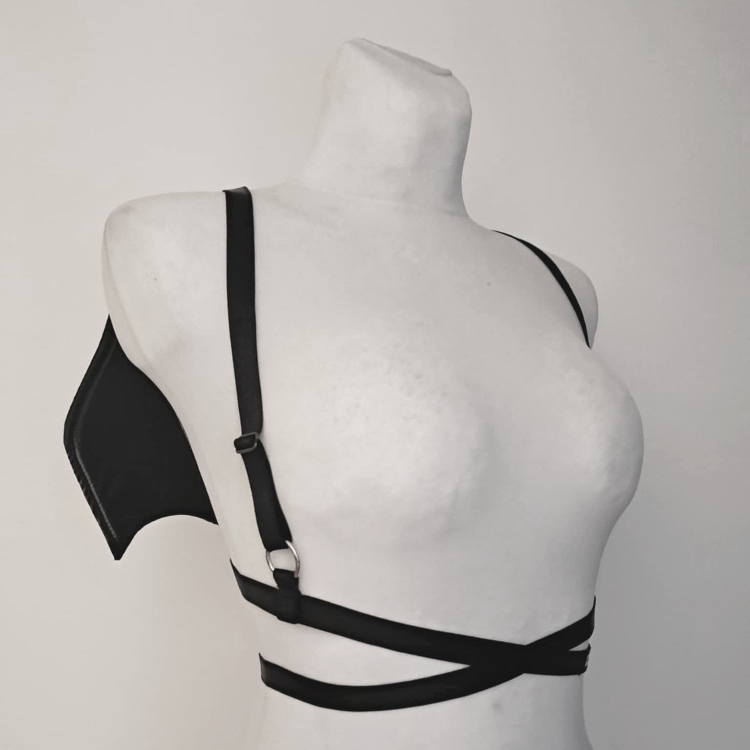 Black harness with bat wings on a mannequin against a gray background