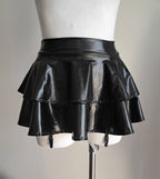 Blackwet-look mini skirt with suspenders on a mannequin against a neutral background