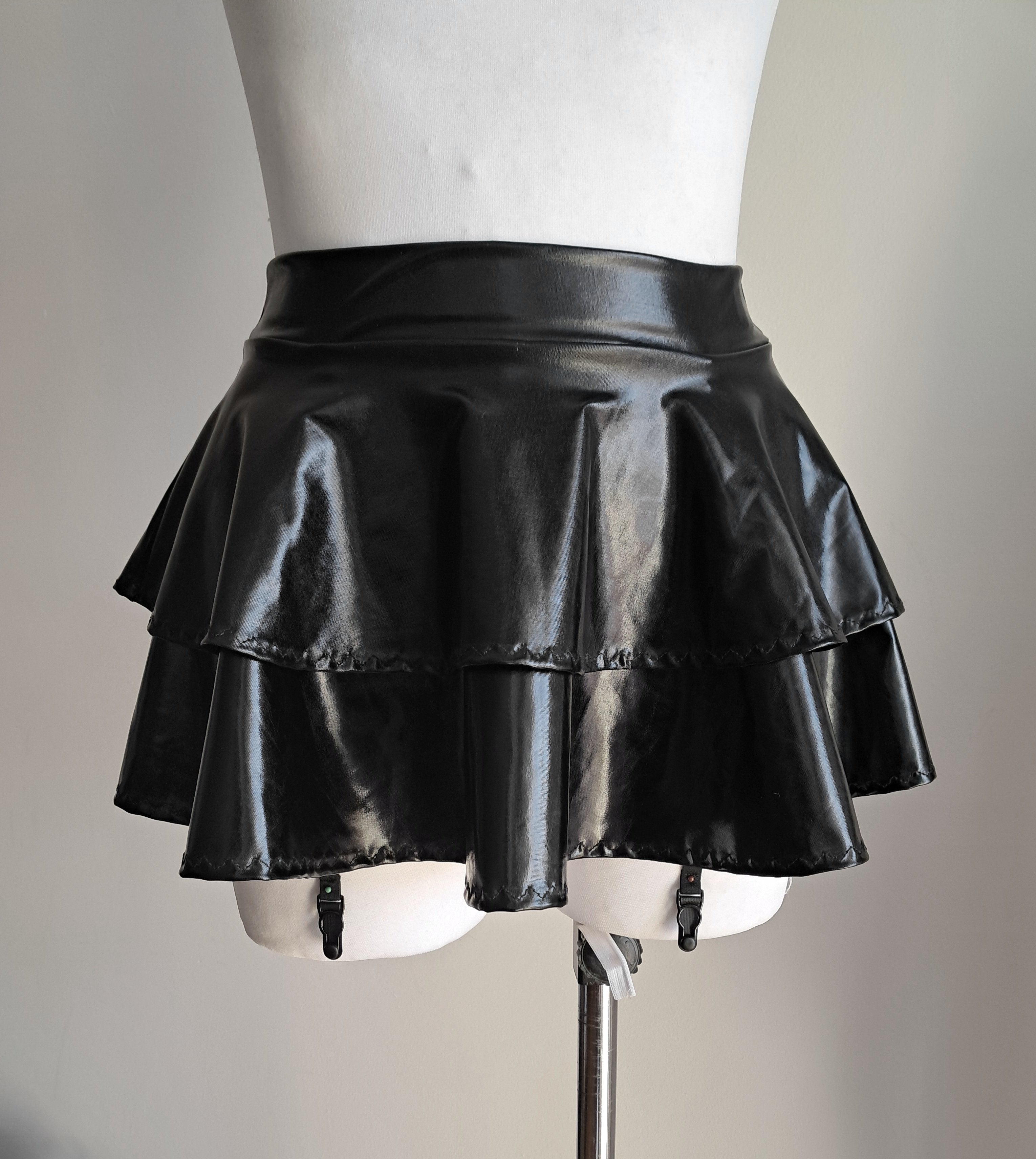 Blackwet-look mini skirt with suspenders on a mannequin against a neutral background