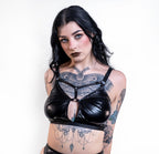 Woman wearing a black wet look bra  with tattoos on a white background