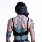 Person wearing a black wet look bra  with mermaid tattoo design on a white background