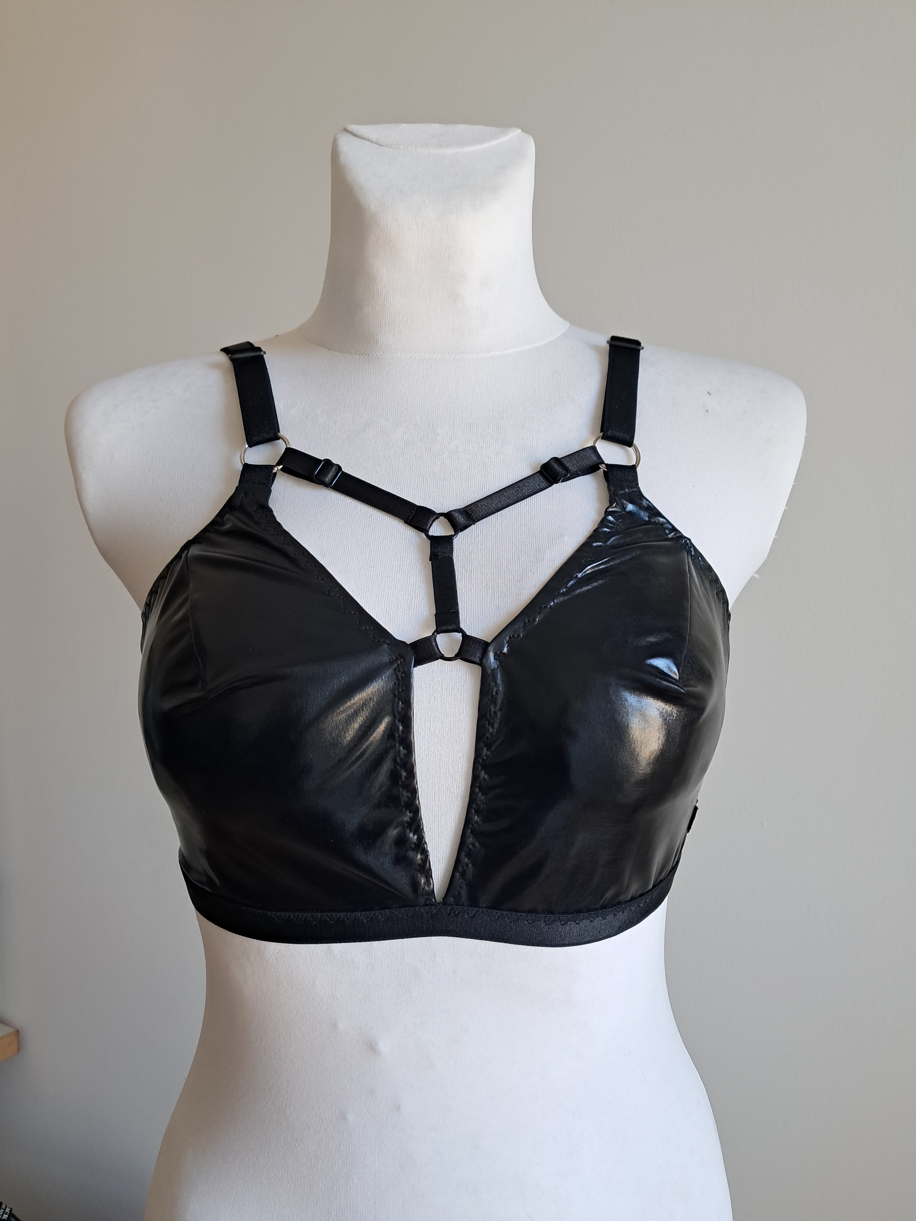 Black wet look bra  on a mannequin bust against a neutral background
