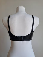 Black wet look bra  on a mannequin against a plain background