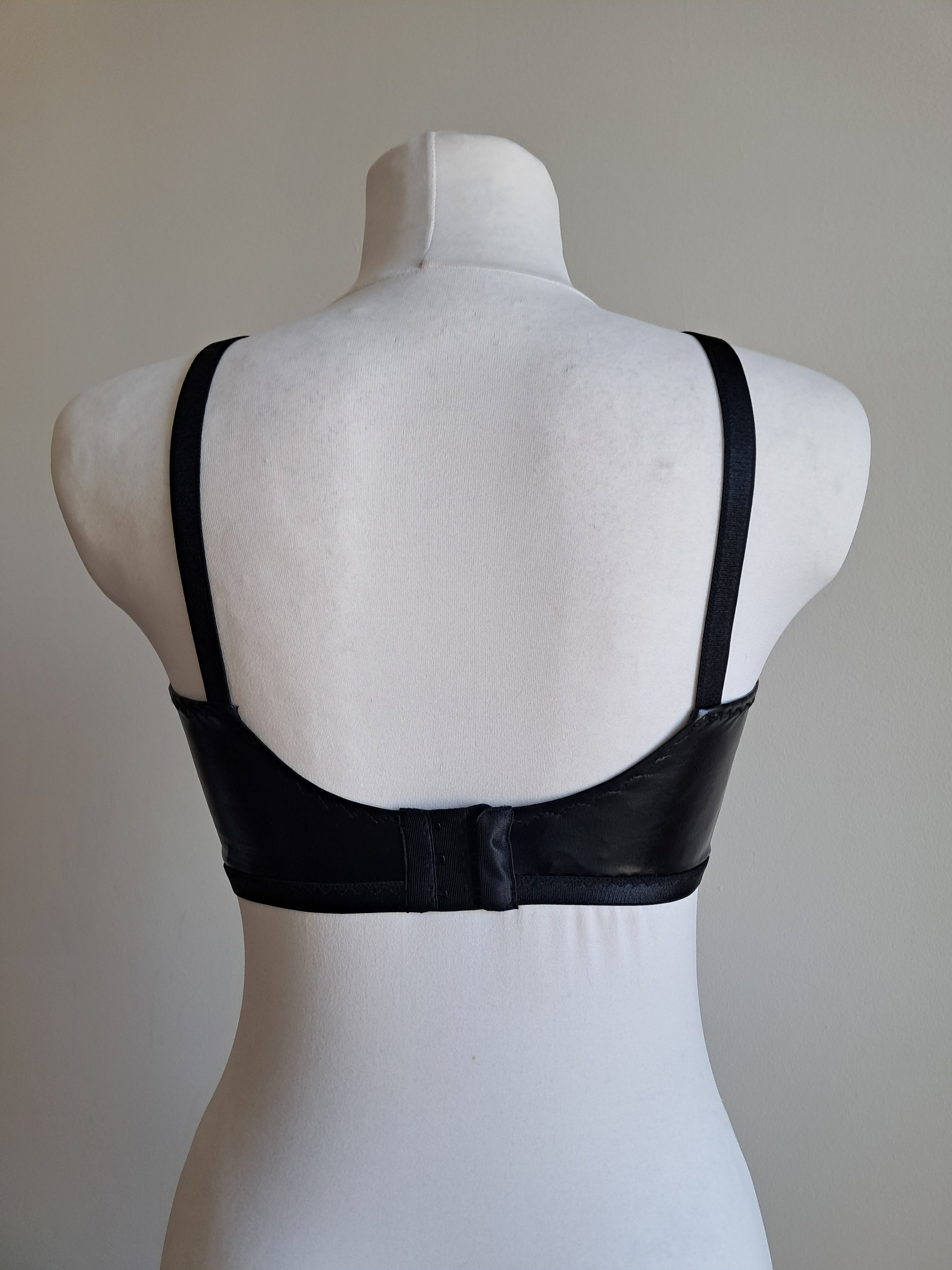 Black wet look bra  on a mannequin against a plain background