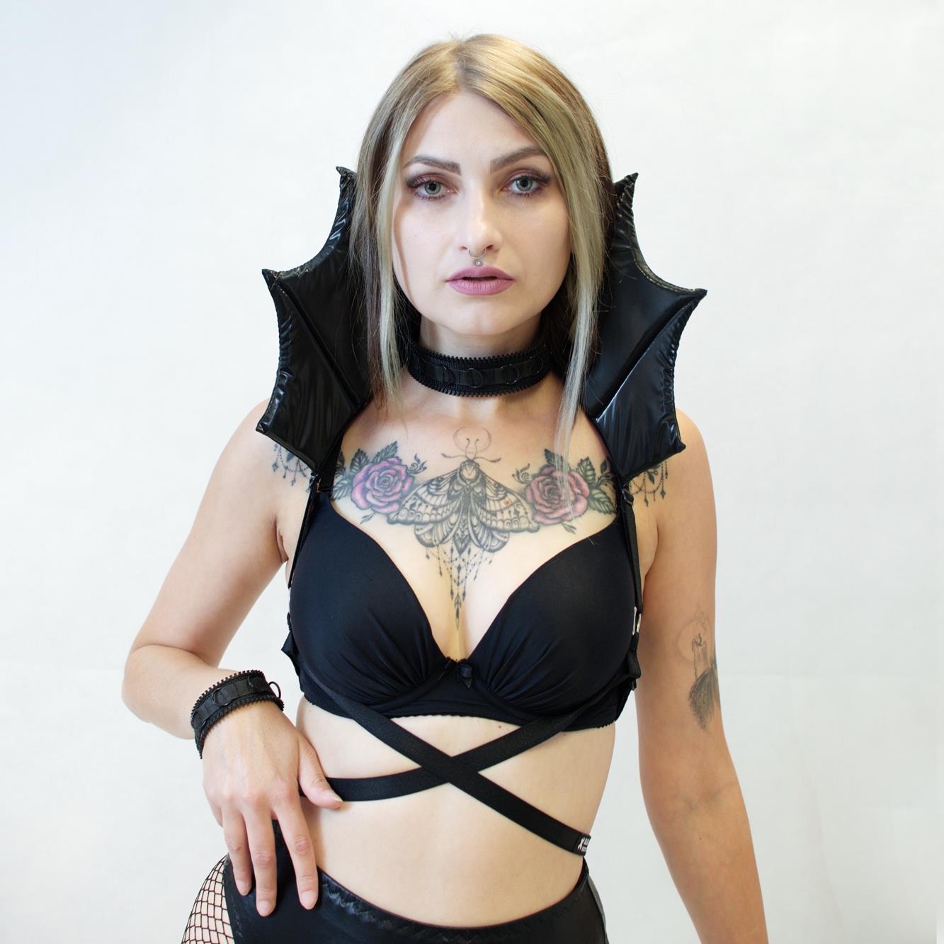 Woman wearing a black vampire collar harness against a white background