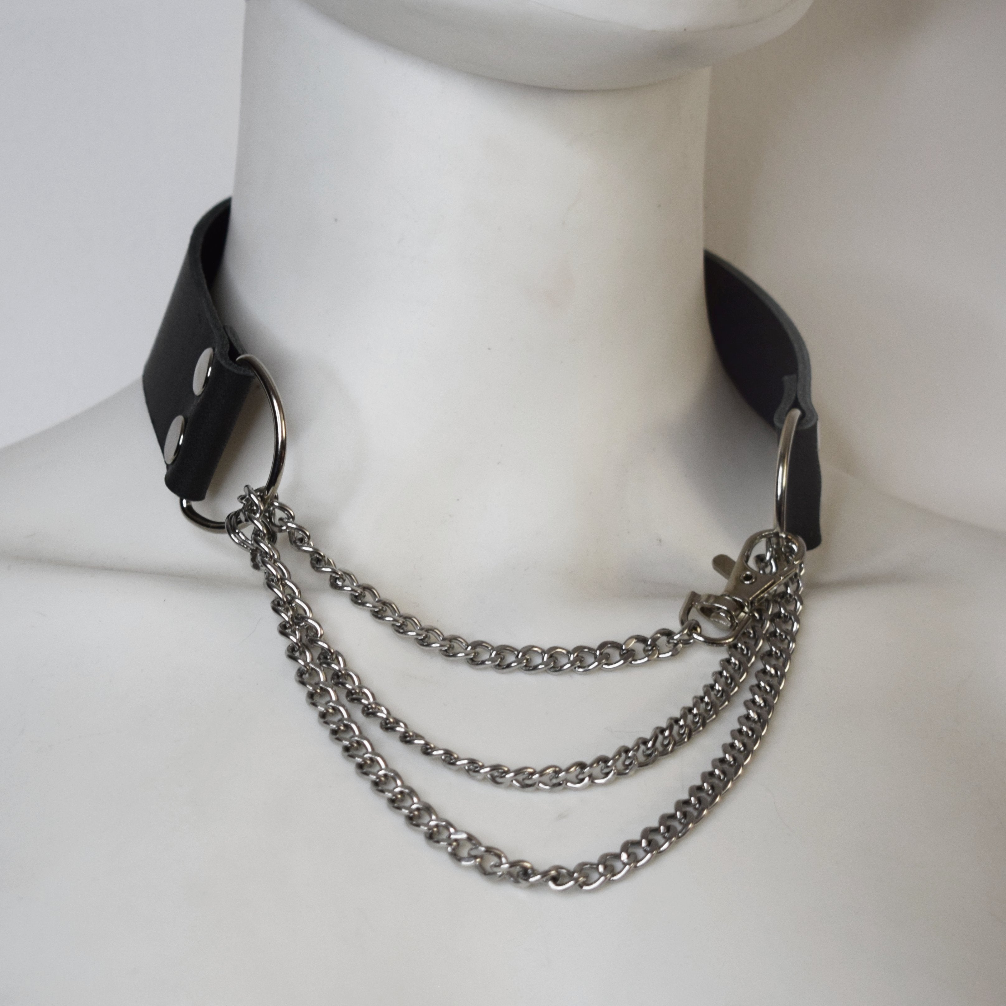 Black leather collar with silver chain on a mannequin neck.