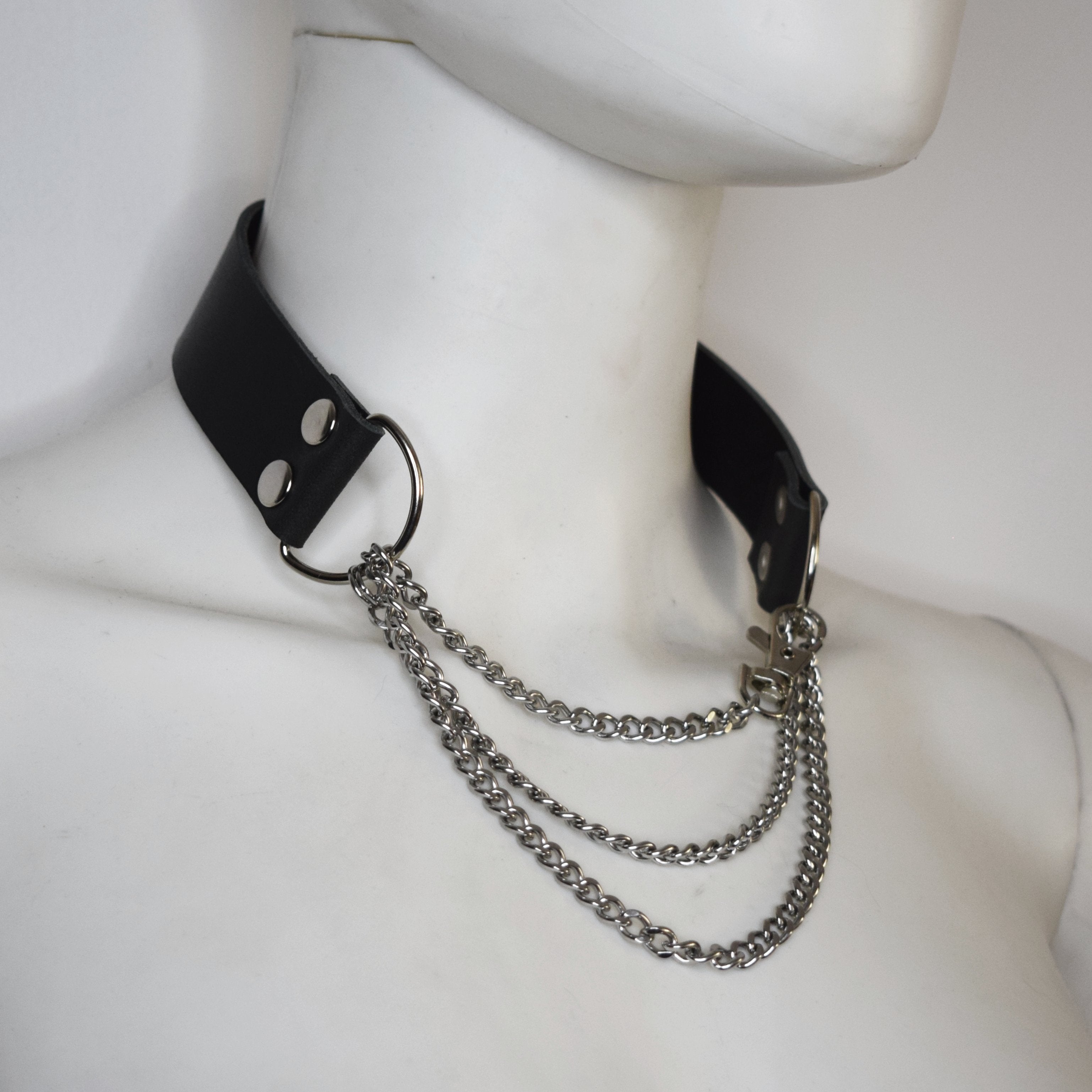 Black leather choker with silver chains on a mannequin neck.