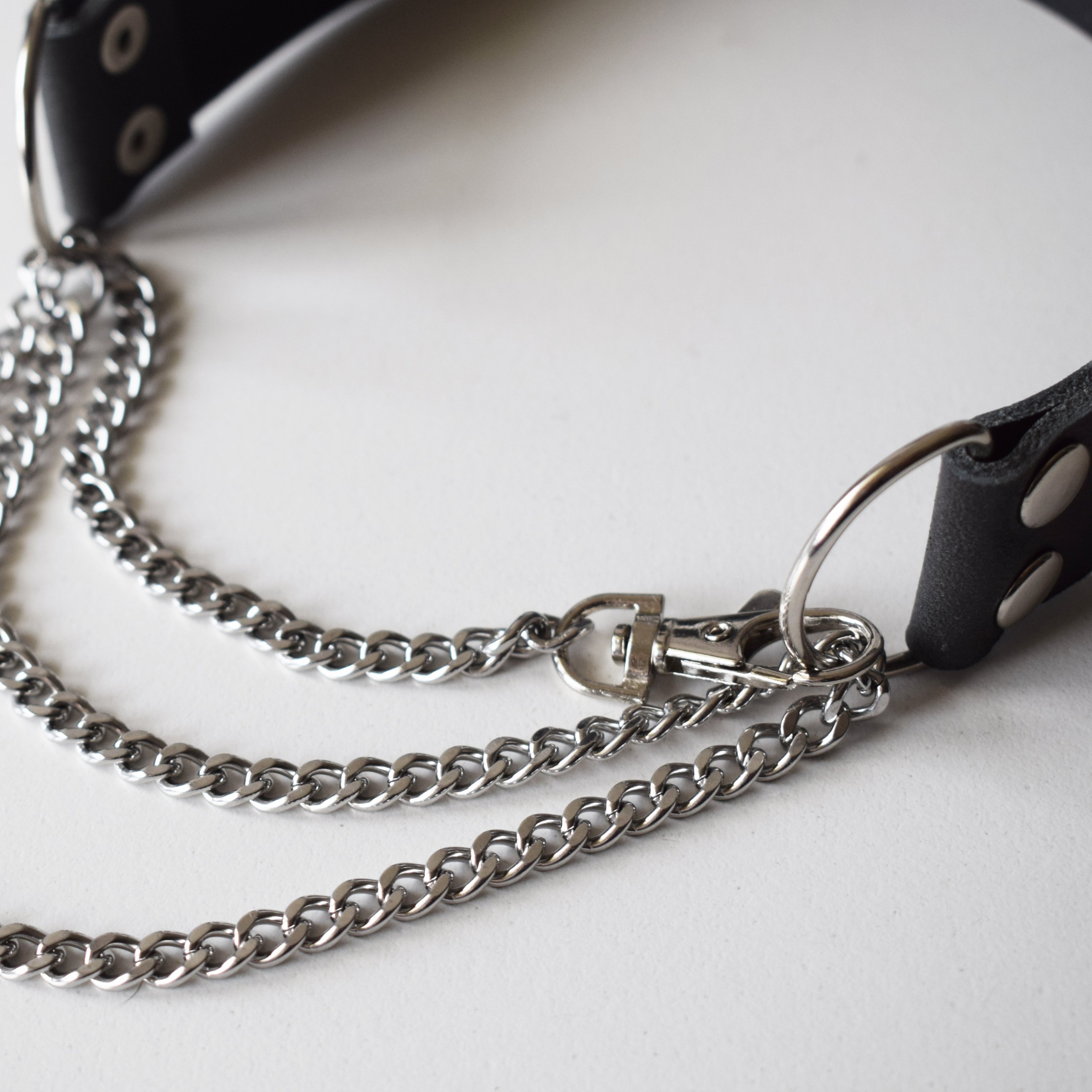 Black leather choker with silver chain on a white background