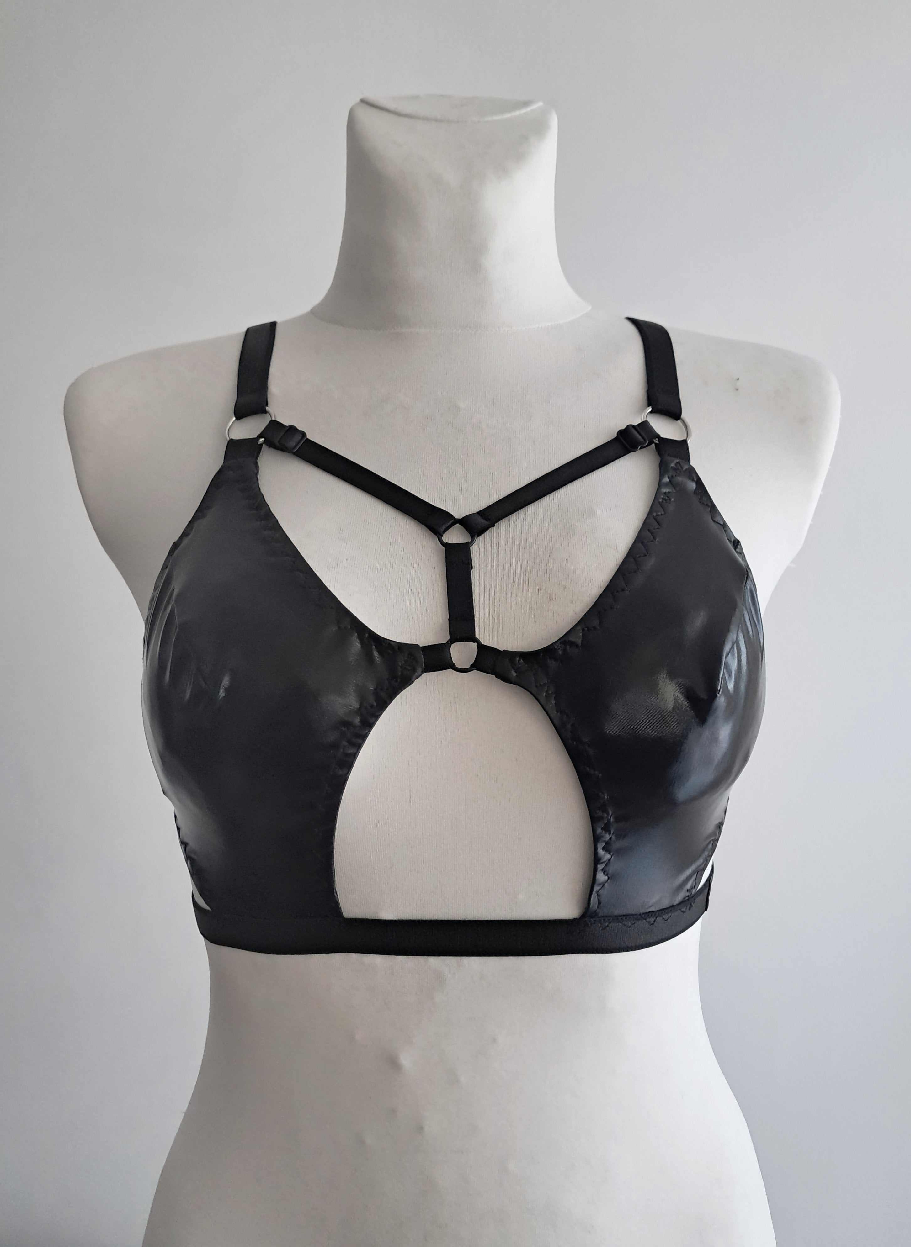 Black cut-out wet look bra on a mannequin against a plain background