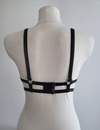 Black cut-out wet look bra on a mannequin against a gray background