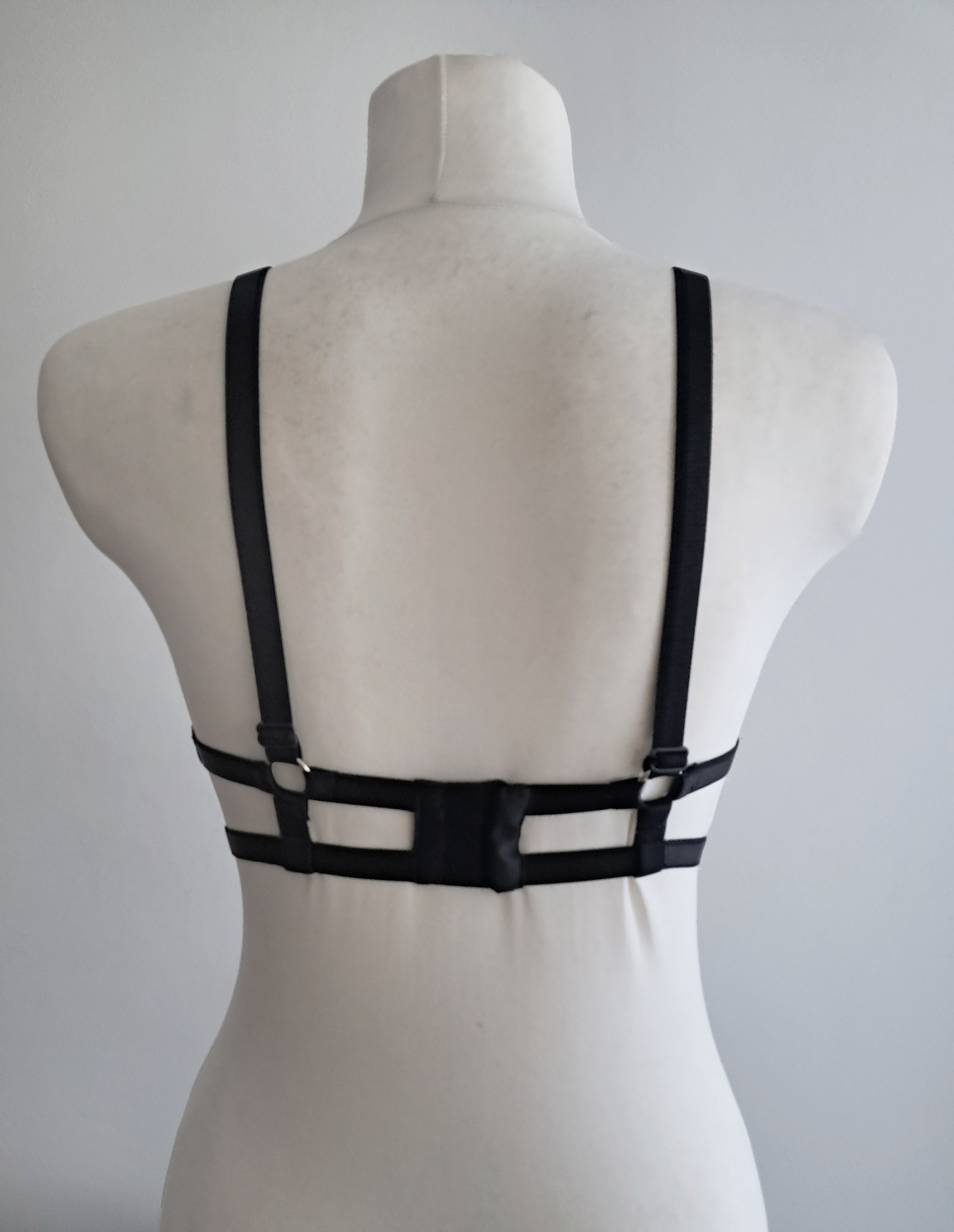 Black cut-out wet look bra on a mannequin against a gray background
