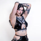 Woman wearing a black cut-out wet look bra with intricate designs on a white background