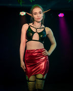 Person wearing a cut-out wet look bra and red skirt on a dark background