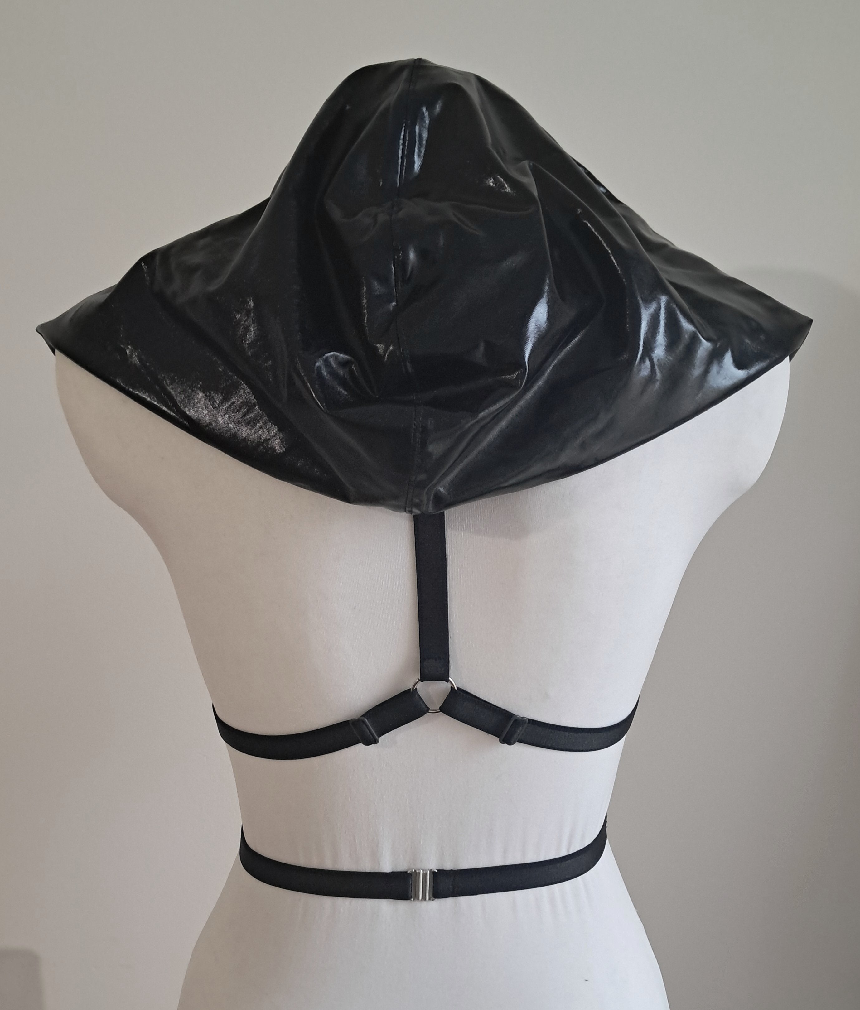 Black wet look hood harness on a mannequin against a plain background