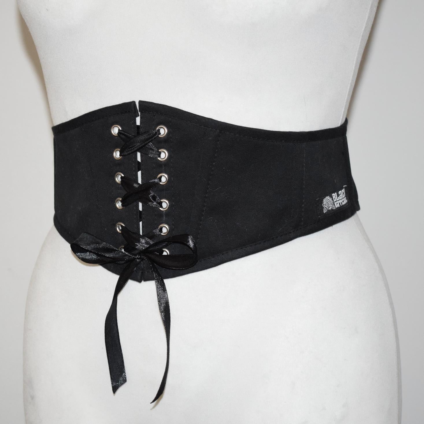 Black corset belt with lace-up design on a mannequin against a white background