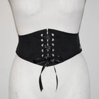 Black corset belt with silver eyelets on a mannequin against a white background