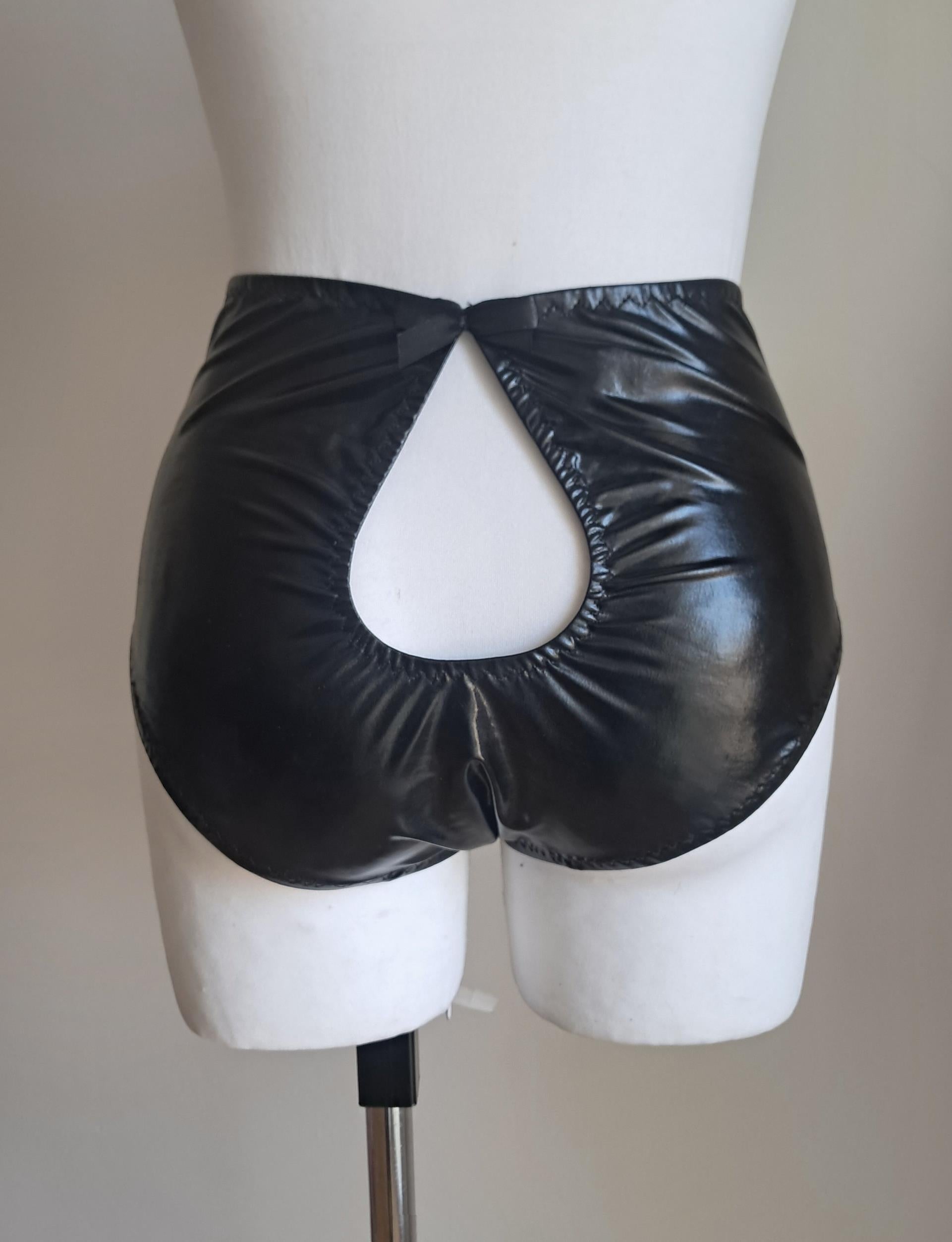 Black wet-look cut-out panties on a mannequin against a plain background