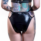 Black wet-look cut-out panties worn by a person with tattoos on a white background