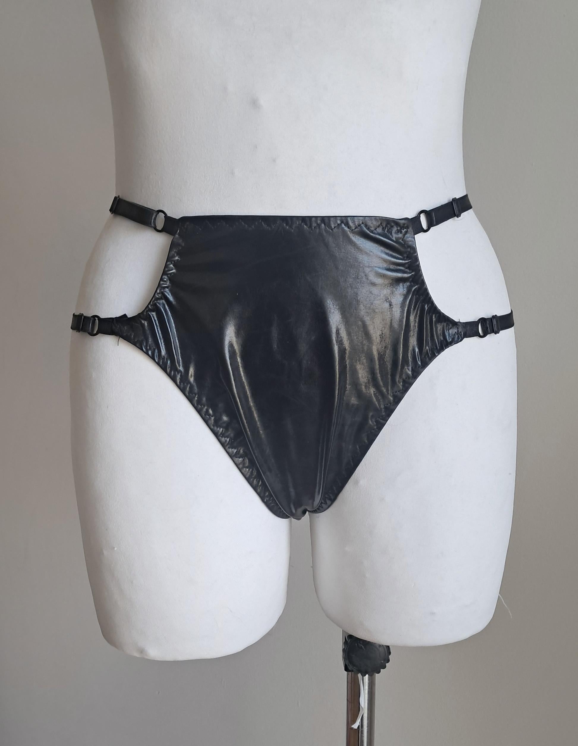 Black wet-look cut-out panties on a mannequin against a plain background