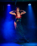 Person in a red wet look wrap bra and black skirt posing on a stage with blue lighting