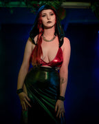 Woman in a red wet look wrap bra and black skirt against a dark background