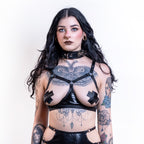 Woman wearing a black open cup wet look bra with tattoos on a white background