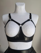 Black open cup wet look strappy bra on a mannequin against a neutral background