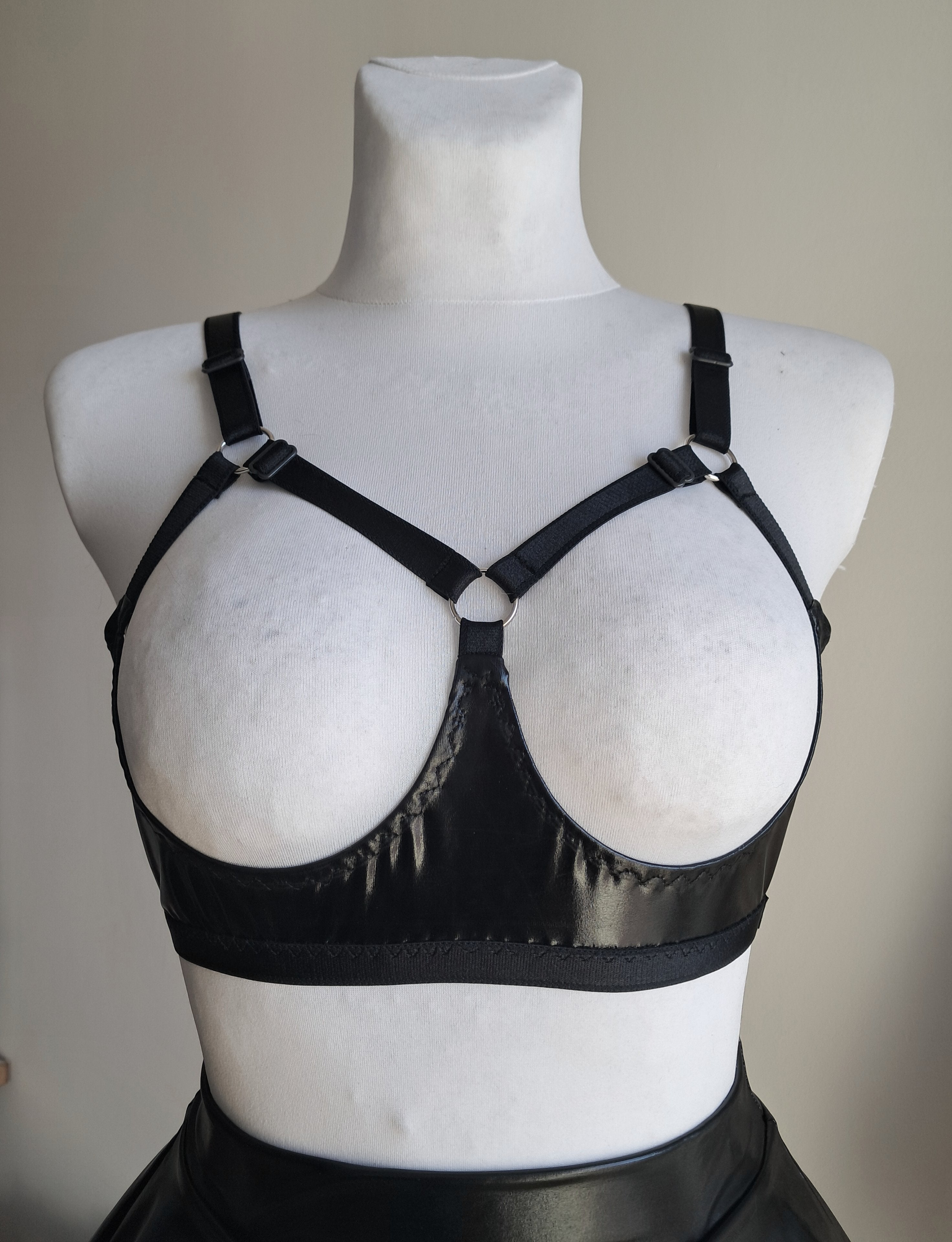 Black open cup wet look strappy bra on a mannequin against a neutral background