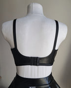 Black open cup wet look bra on a mannequin with a plain background