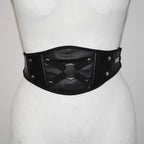 Black leather belt with metallic accents on a mannequin against a white background