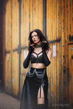 Woman in black wet-look cut-out maxi skirt standing against a wooden door background