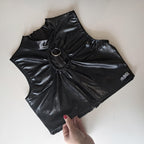 Black wet-look sleeveless crop top held by a hand on a white background