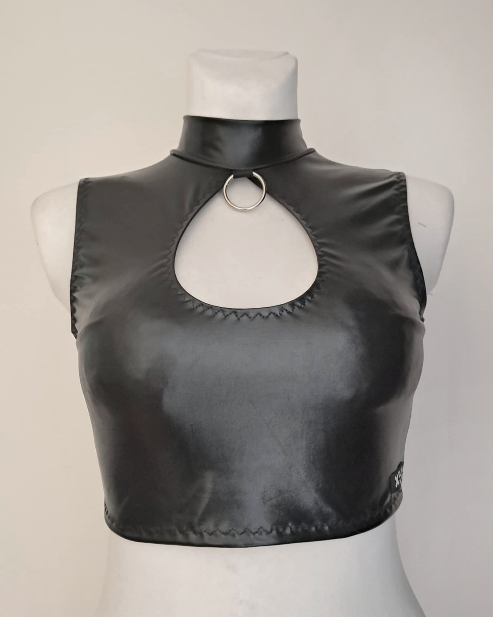 Black wet-look sleeveless crop top on a mannequin with a plain background