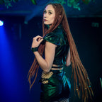 Woman with long braided hair wearing a wet-look sleeveless crop top on a dark background