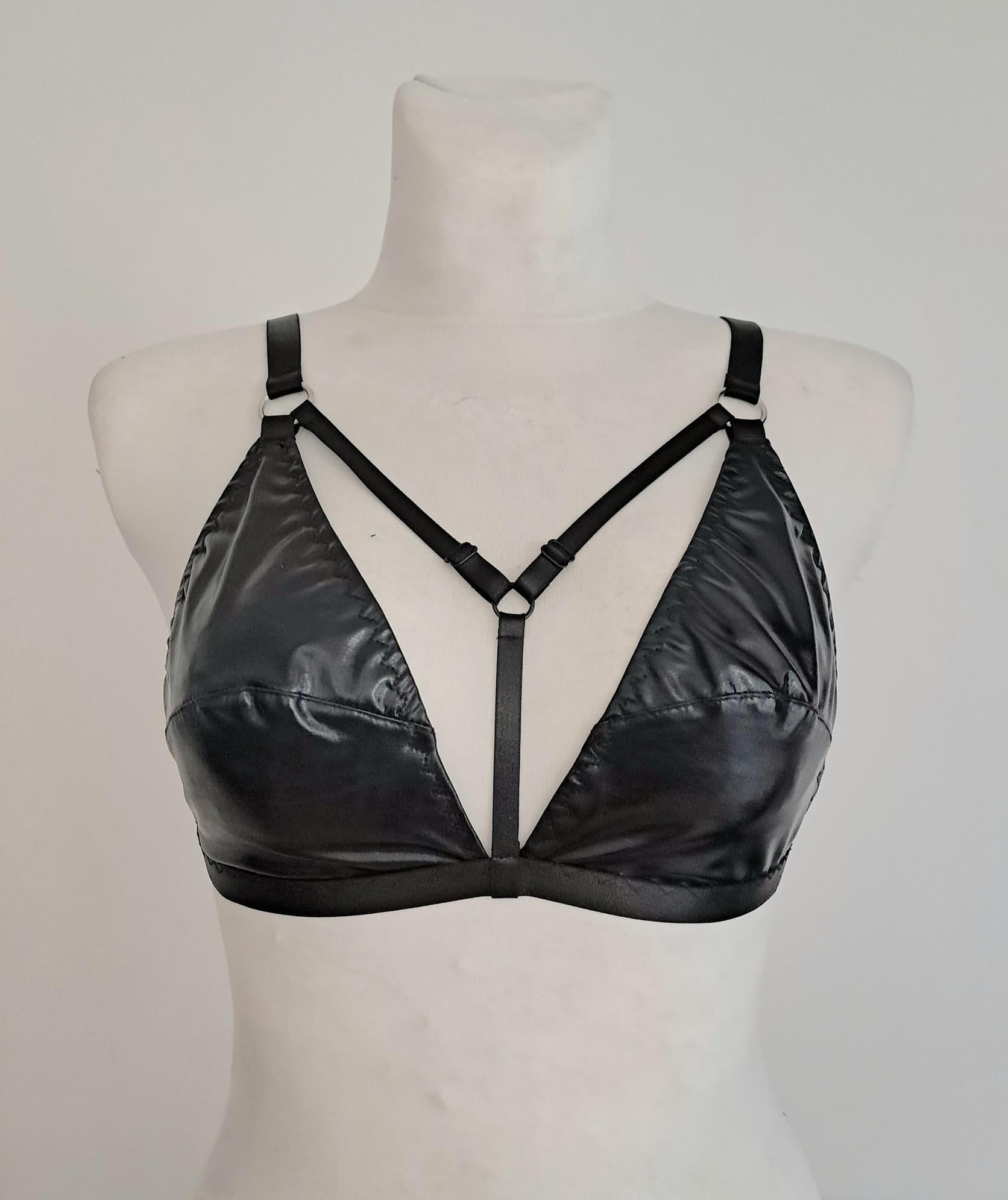 Black wet look triangle bra on a mannequin against a plain background