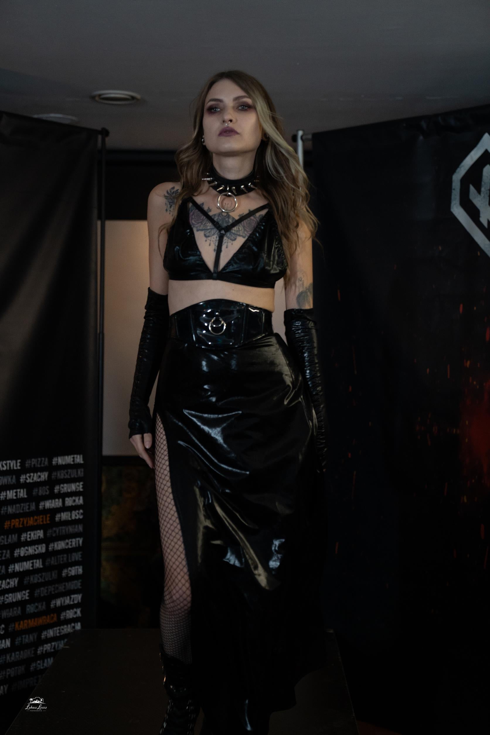 Person wearing a black wet look triangle bra with a dark background